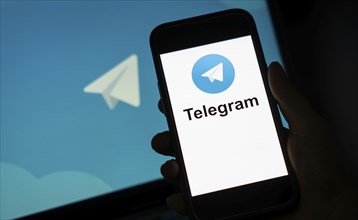 The social media Telegram messenger logo is being displayed on a smartphone screen and on a