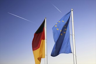 German and European flags against a blue sky