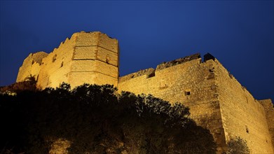 Night shot, view of a castle ruin illuminated at night, surrounded by dark nature and rocky