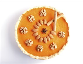 Traditional american sweet pumpkin pie decorated with nuts, isolated on white background. top view