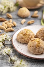 Almond cookies and a cup of coffee on a gray wooden background and green linen textile. Side view,