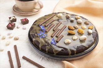 Homemade chocolate brownie cake with caramel cream and almonds with cup of coffee on a white