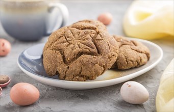 Homemade oatmeal cookies with a cup of cocoa and a yellow textile on a gray concrete background.