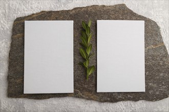 White paper business card, mockup with natural stone and boxwood branch on gray concrete background