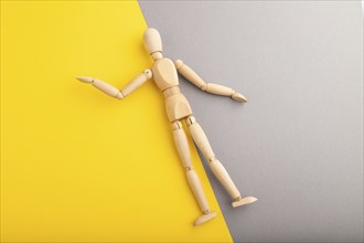 Wooden mannequin lies on gray and yellow pastel background. copy space, isolated, presentation