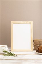 White wooden frame mockup with cup of coffee and cake on brown background. Blank, side view, still