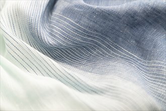 Fragment of blue and white linen tissue. Side view, textile blurred background and texture. Water