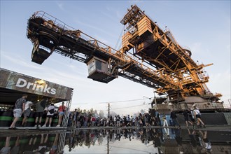 An open-cast mining excavator is reflected in a puddle at the Melt Festival in Ferropolis on 13