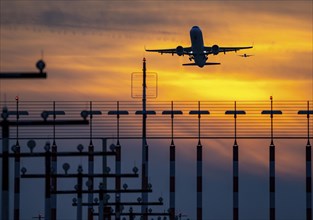 Runway lighting, approach aids, at Düsseldorf International Airport, sunset, aircraft taking off