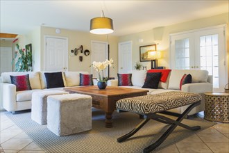 Beige upholstered sofas with colourful cushions, wooden coffee table and zebra motif ottoman in