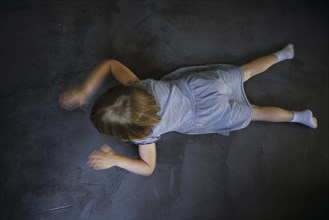 Symbol photo on the subject of tantrums (posed scene) . A little girl is lying on the floor,