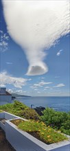 An impressive cloud formation hovers over a tranquil coastal landscape, Sao Joao, Pico Island,