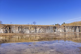 Rock wall in an old abandoned quarry with water reflections