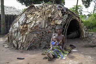 Pygmy woman of the Baka or BaAka people with her child in front of her hut, Bayanga, Sangha-Mbaéré