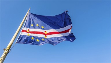 The flag of Cape Verde flutters in the wind, isolated against a blue sky