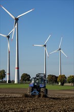 Farmer working in the fields, with a tractor, wind farm above the village of Lichtenau,