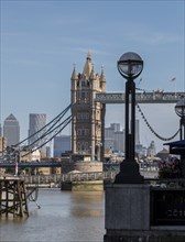 Tower Bridge against a city backdrop and modern skyscrapers, a street lamp in the foreground,