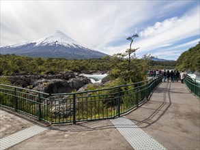 Visitors at the waterfall Saltos de Petrohue, volcano Osorno in the back, chilenean lake district,