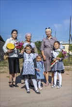 Family and schoolgirl with a bouquet of flowers on the first day of school, Issyk-Kul region,