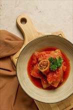 Stuffed cabbage rolls, with minced meat, in tomato sauce, on a beige background, food and drink,