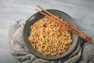 Instant noodles, in a bowl, on a gray table, top view, no people