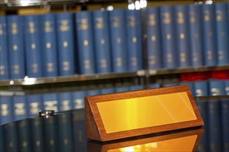 Brass sign with space for text in front of a large bookshelf