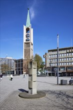 Old town church of the Ev. Emmaus parish against blue sky and stele at Heinrich-König-Platz in