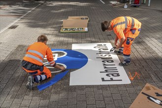 Application of road markings for a cycle lane, Rüttenscheider Straße in Essen, in the shopping and