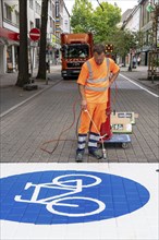 Application of road markings for a cycle lane, Rüttenscheider Straße in Essen, in the shopping and