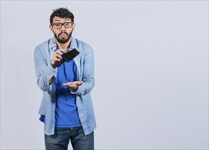 Sad man holding empty wallet and looking at the camera isolated. Unhappy and surprised man holding