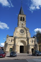 Historische Kirche mit großem Glockenturm und steinerner Fassade unter blauem Himmel mit Wolken in