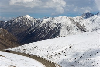 Verschneite Berge und eine kurvenreiche Straße in einer winterlichen Landschaft in Andorra,