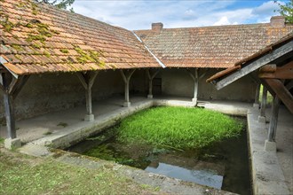 Washhouse in Montaigu-le-Blin village features a grassy basin, Allier. Auvergne-Rhone-Alpes,