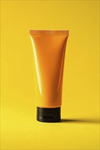 Orange sunscreen tube on yellow studio background. KI generiert, generiert, AI generated