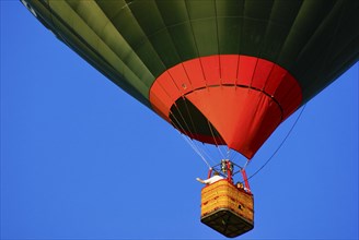 A hot air balloon rises into the air with passengers on board, as part of the aviation festival on