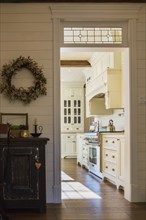 White painted maple wood antique style cabinets with tan coloured quartz countertops in kitchen