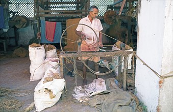 Indian worker winding coils in the Labourers Coir Mats and Mattings Cooperation, coir mat