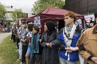 A human chain in front of a tent and an All eyes on Rafah sign during the occupation of the