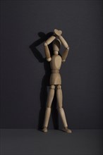 Wooden mannequin stands with raised hands on gray background. protest, attention concept. copy