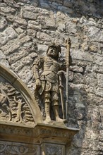 Stone figures, statue, male warrior above portal, detail, armour, weapons, decoration,