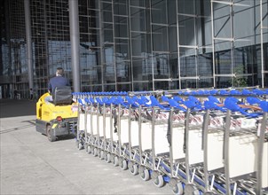 Man driving vehicle collecting trolleys at Malaga airport, Spain, Europe