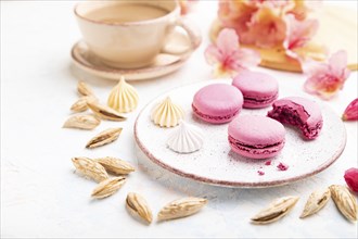 Purple macarons or macaroons cakes with cup of coffee on a white concrete background decorated with