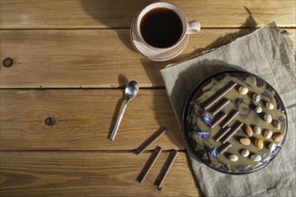 Homemade chocolate brownie cake with caramel cream and almonds with cup of coffee on wooden