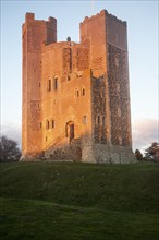 Late afternoon winter sunshine shining on walls of Orford Castle, Orford, Suffolk, England, United