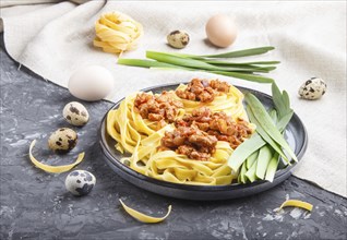 Tagliatelle bolognese pasta with minced meat on a black concrete background. side view, close up