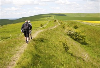 Two men walking along the ditch and embankment of the Wansdyke a Saxon defensive structure on All