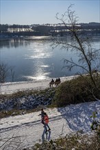 Winter in the Ruhr area, Lake Baldeney, snow-covered, partly frozen lake, walkers on the lakeside