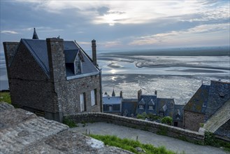 Historic houses of the monastery island Le Mont Saint Michel, behind it mudflats, low tide, shortly