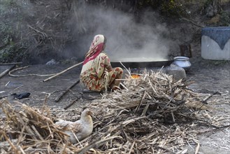 Workers boiling sugarcane juice as they are making Gur (jaggery) in a village on December 10, 2021