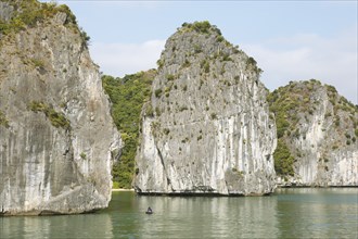 Tiny fishing boat and the huge karst rocks in Lan Ha Bay, Halong Bay, Vietnam, Asia